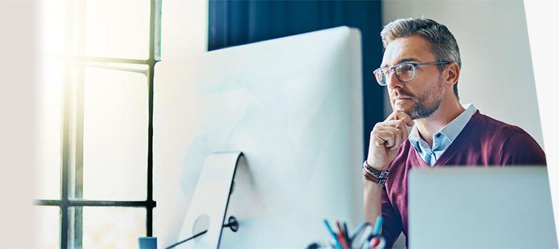 A man sitting at a computer looking at the computer screen.